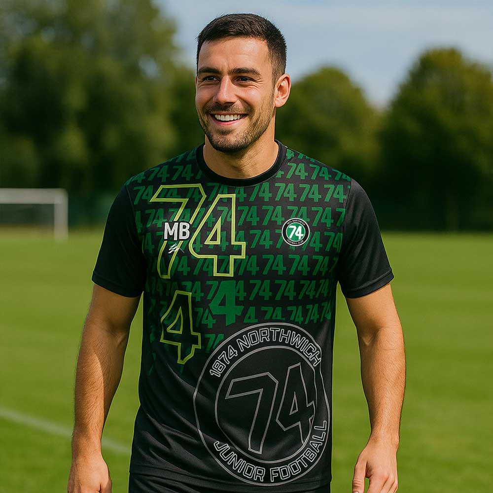 model wearing 1874 Northwich JFC T-Shirt – Adult on a sunny sports field 