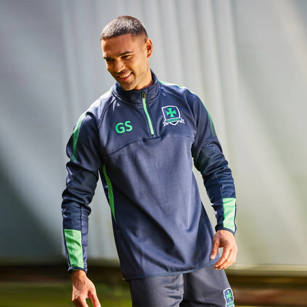 Man wearing a navy Edge midlayer with green accents and logos