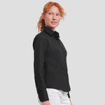 Side view of Model wearing the Russell Collection Ladies Long Sleeve Fitted Poplin Shirt 924F in Black