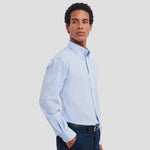 Side view of model wearing the Russell Collection Long Sleeve Easy Care Oxford Shirt 932M in Oxford Blue