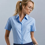 Model wearing the Russell Collection Ladies Short Sleeve Easy Care Oxford Shirt 933F in Oxford Blue