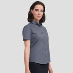 Model wearing the Russell Collection Ladies Short Sleeve Easy Care Poplin Shirt 935F in Convoy Grey
