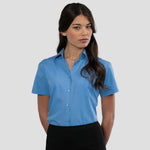 Model wearing the Russell Collection Ladies Short Sleeve Easy Care Poplin Shirt 935F in Corporate Blue