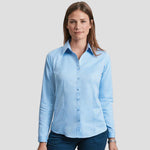 Model wearing the Russell Collection Ladies Long Sleeve Herringbone Shirt in Light Blue