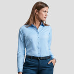 Model wearing the Russell Collection Ladies Long Sleeve Herringbone Shirt 962F in Light Blue