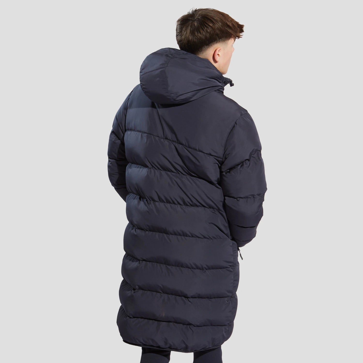 Rear view of model wearing the the Chadwick Teamwear Youth Chevron Puffer Coat in Navy.