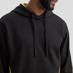 Person wearing a black Uneek Two Tone Hooded Sweatshirt UC517 with yellow accents