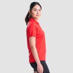 Model wearing the AWDis Ladies Cool Polo Shirt JC0045 in Fire Red