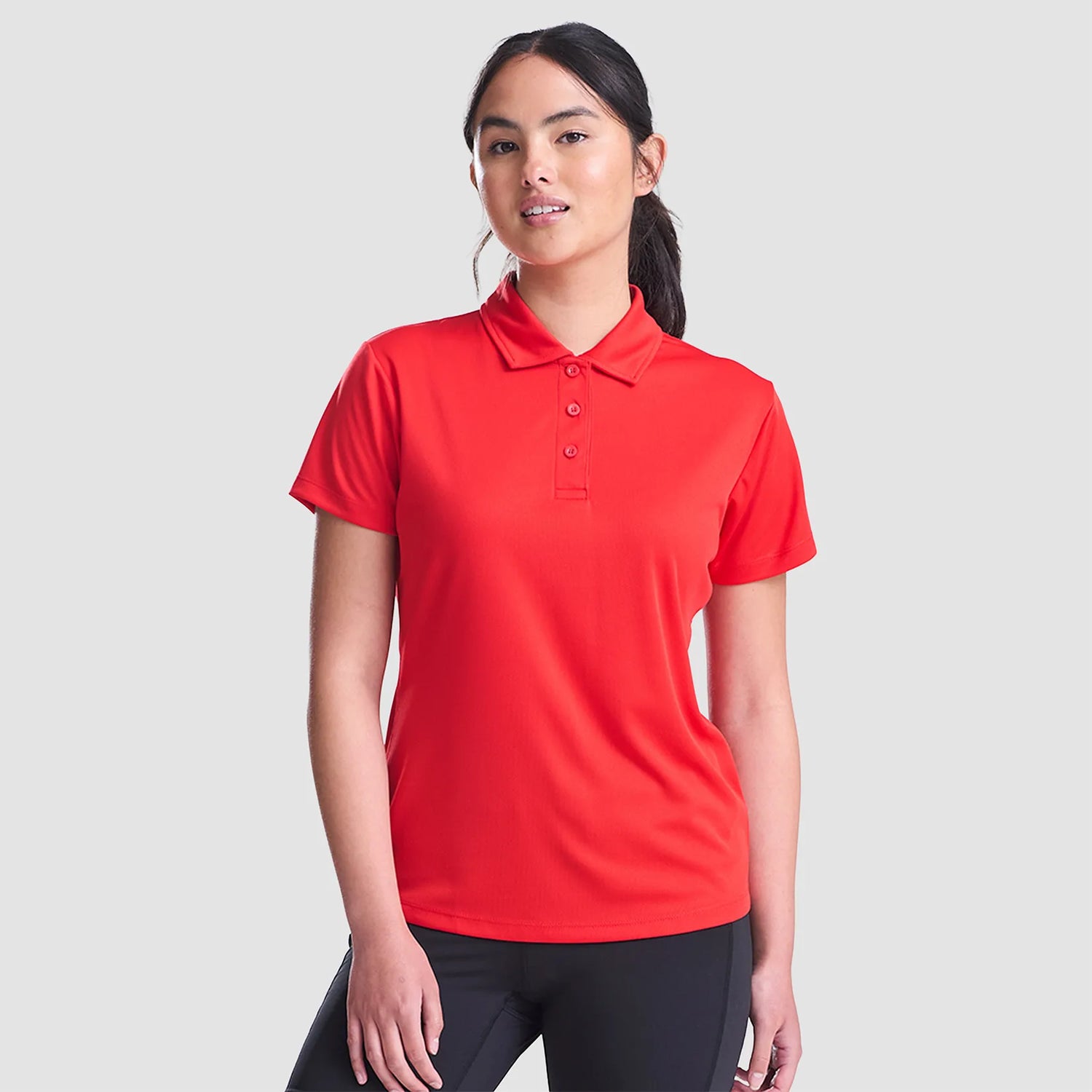 Model wearing the AWDis Ladies Cool Polo Shirt JC0045 in Fire Red