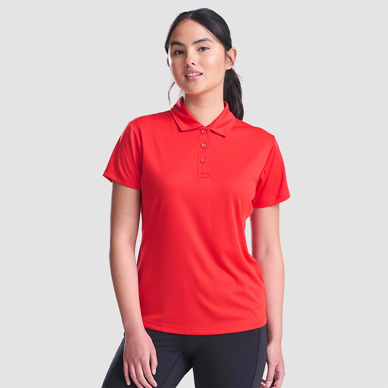 Model wearing the AWDis Ladies Cool Polo Shirt JC0045 in Fire Red