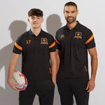 Two men wearing black sports tech kinetic polo shirts with amber accents, one holding a rugby ball