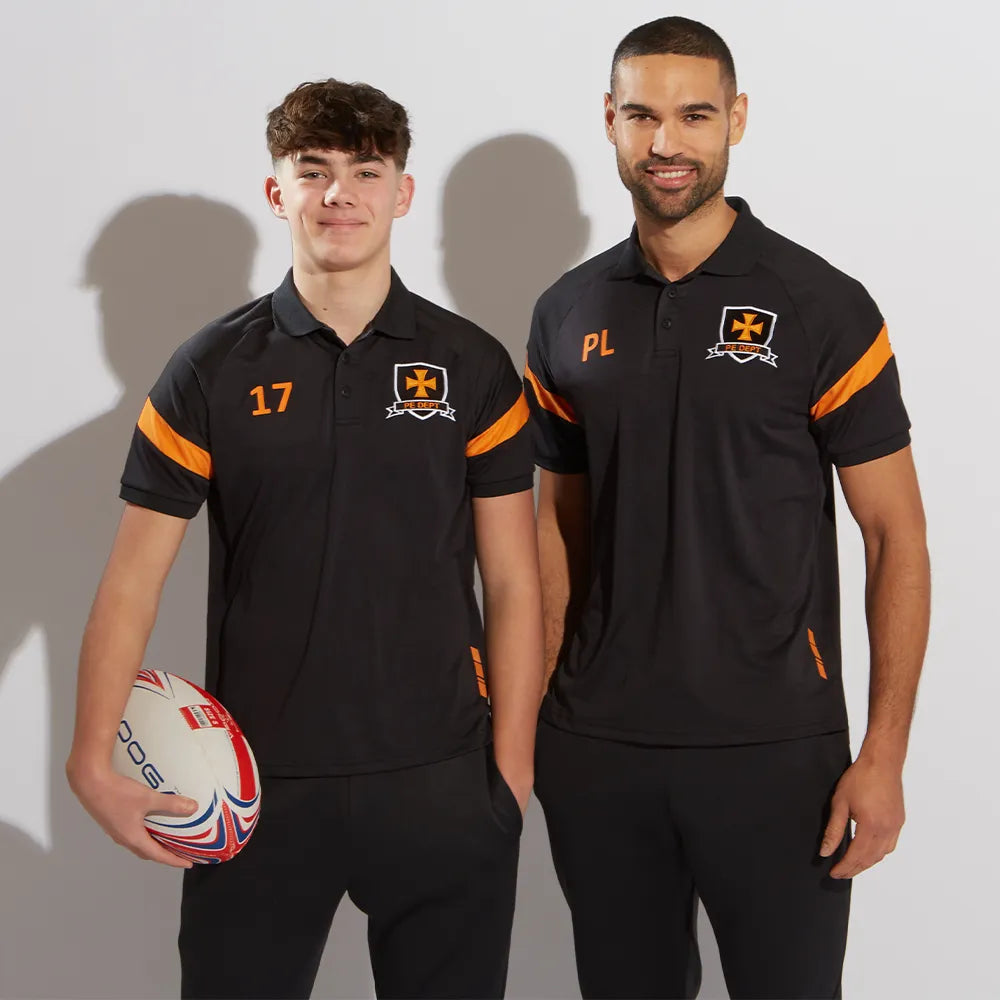Two men wearing black sports tech kinetic polo shirts with amber accents, one holding a rugby ball