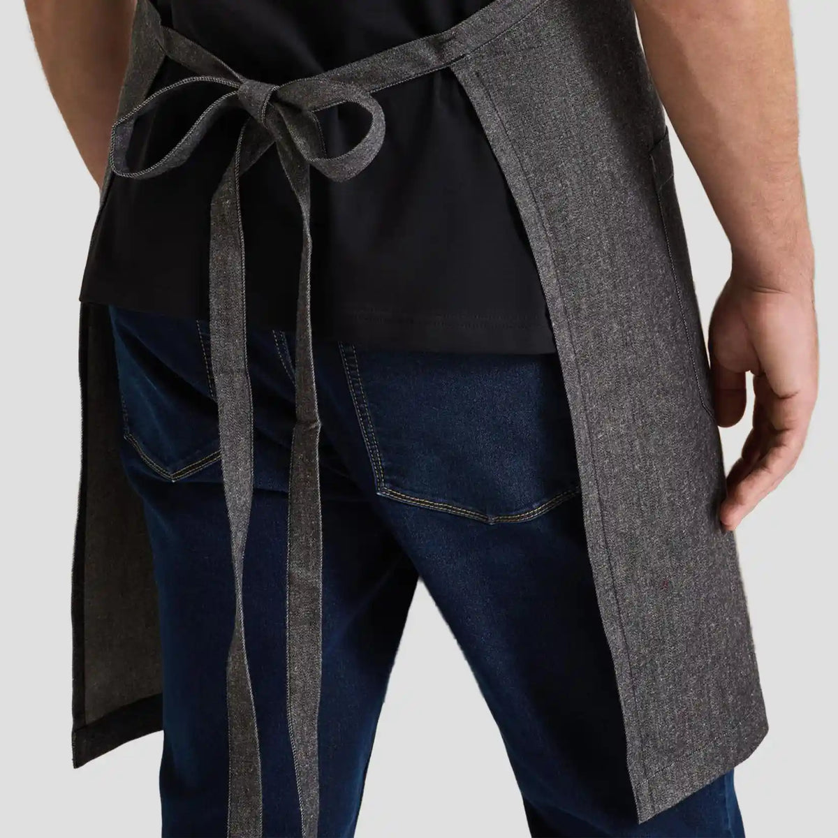 Back view of model wearing the Premier Fairtrade Organic Cotton Denim Bib Apron PR113.