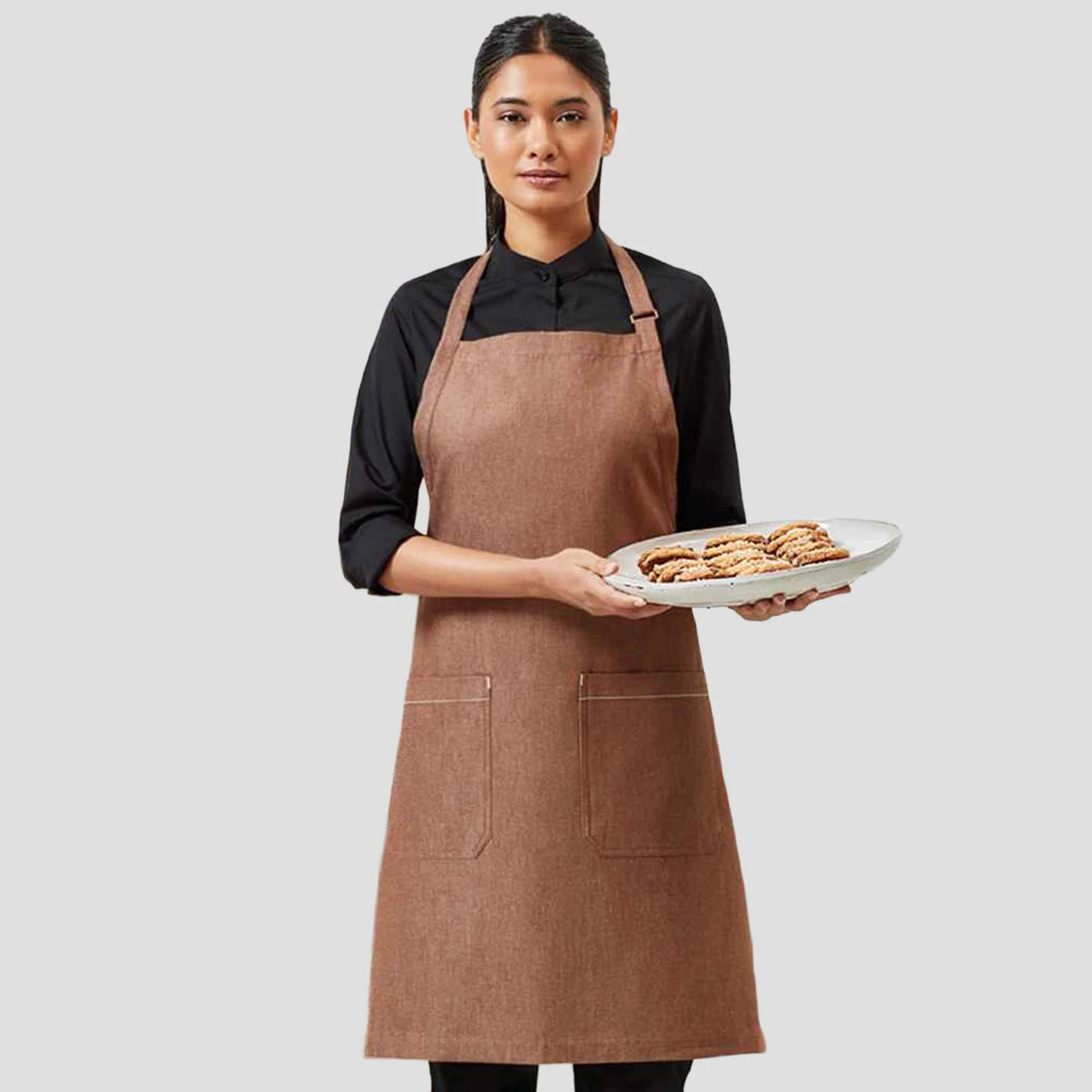 Model wearing the Premier Fairtrade Organic Cotton Denim Bib Apron PR113.