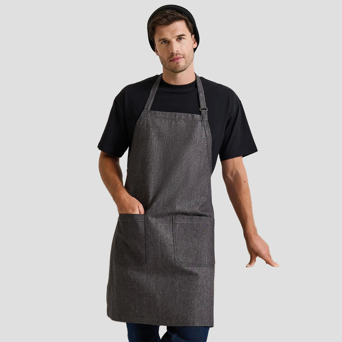 Model wearing the Premier Fairtrade Organic Cotton Denim Bib Apron PR113.