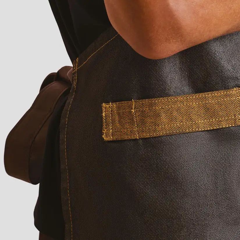 Side view of model wearing the Premier Division Bib Apron PR136.