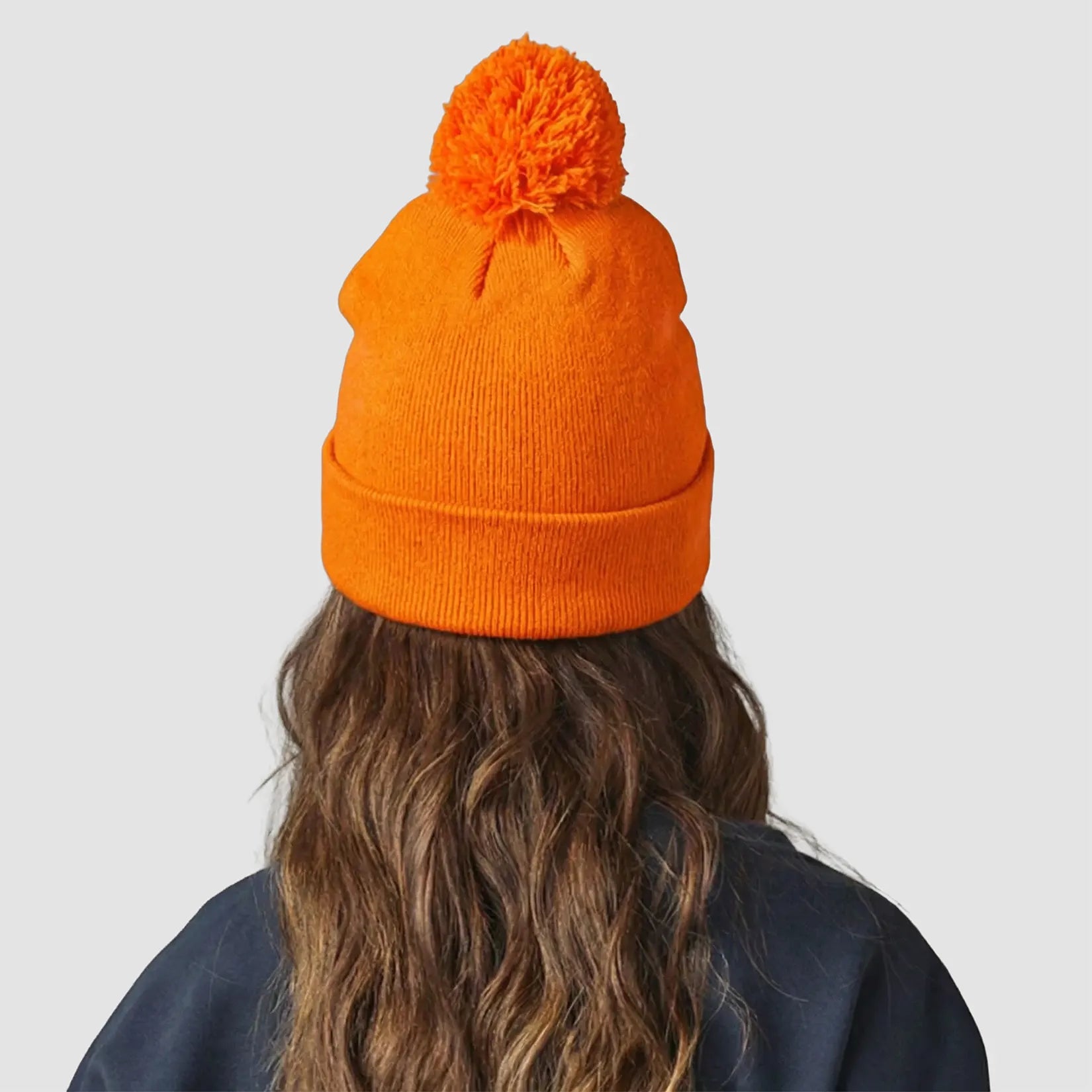 Rear view of model wearing the Winsford ASC Cuffed Bobble Beanie (Orange) BC426